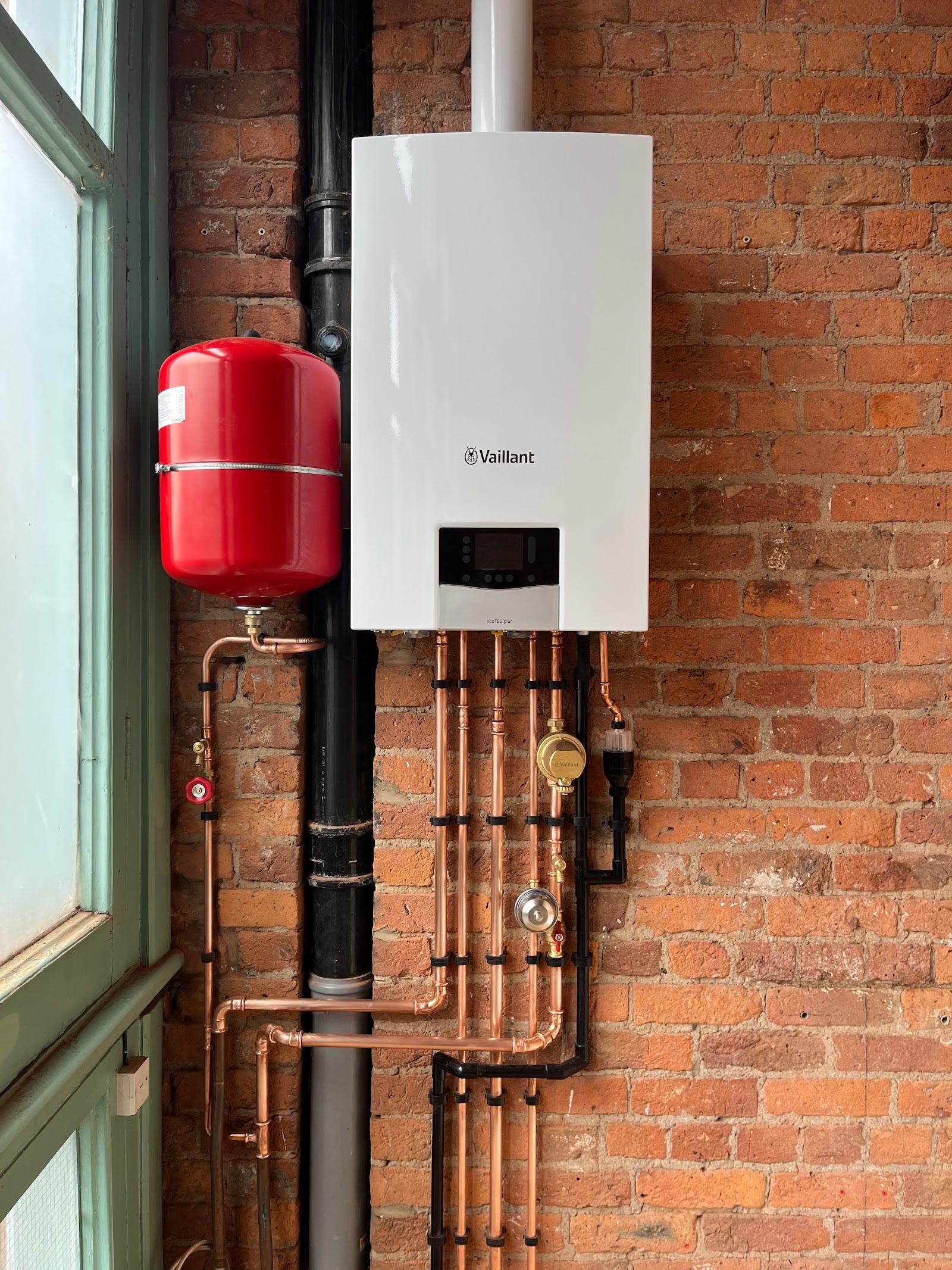 A Vaillant combi boiler on an exposed brick wall with vertical copper pipework