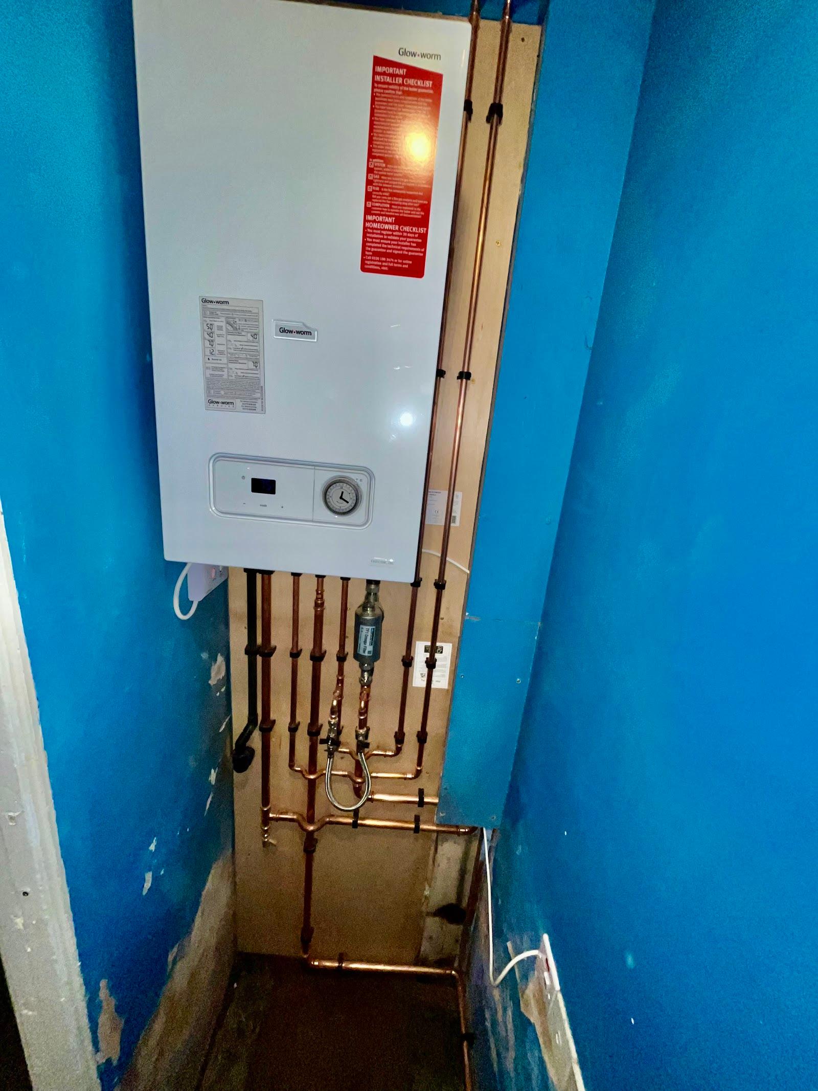 A boiler fitted in a cupboard with the pipework dropped straight down the wall